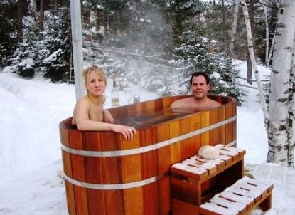 a man and woman sitting in a wooden hot tub