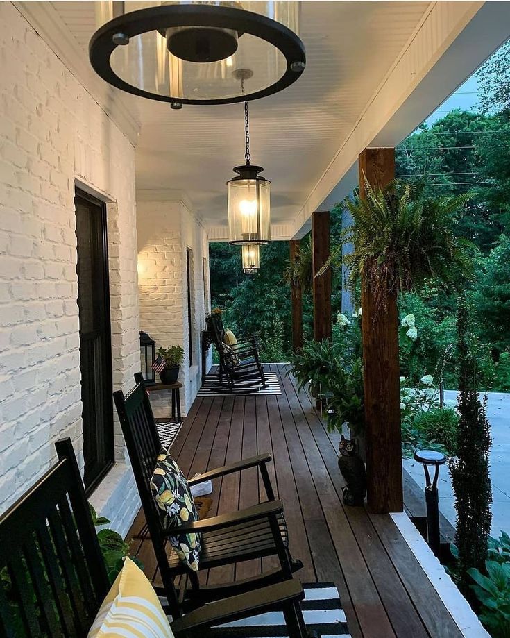 a porch with rocking chairs and plants on it