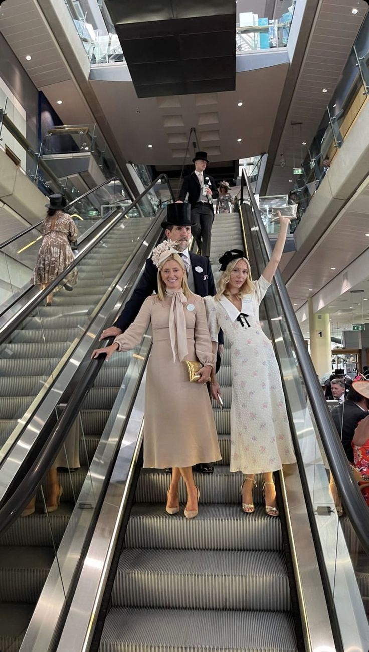 two women standing on an escalator with their arms in the air