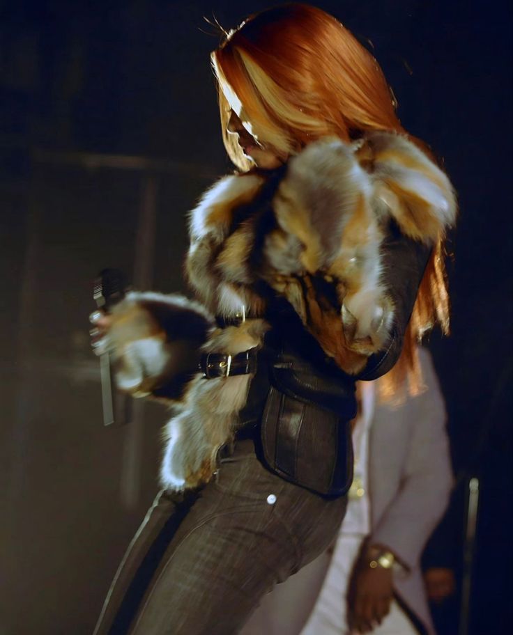 a woman with red hair wearing a fur coat