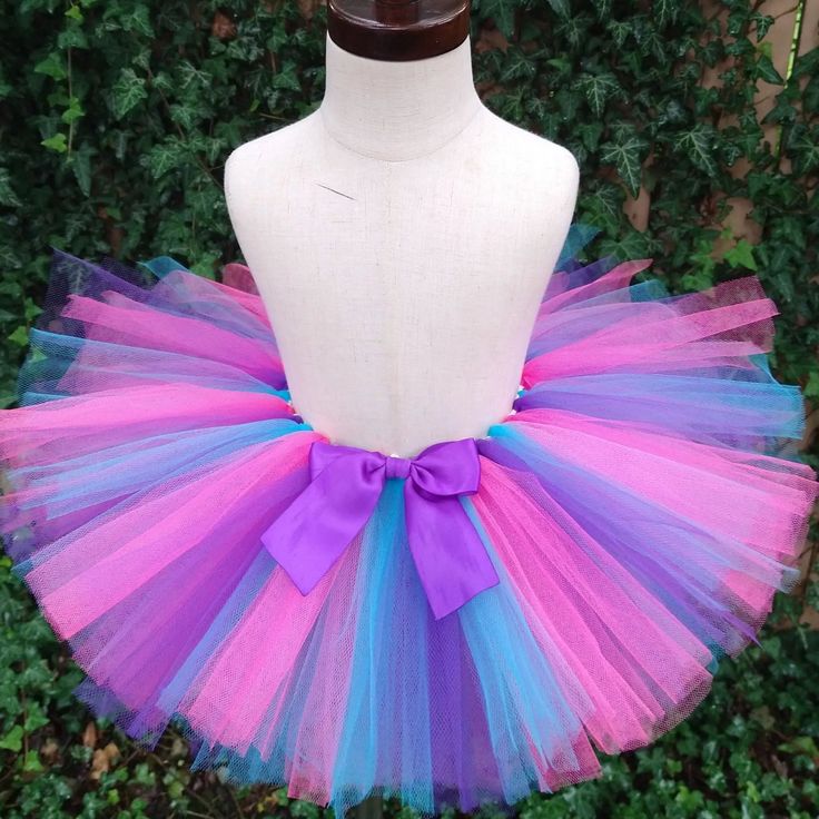 a mannequin wearing a colorful tutu with a purple bow on the top