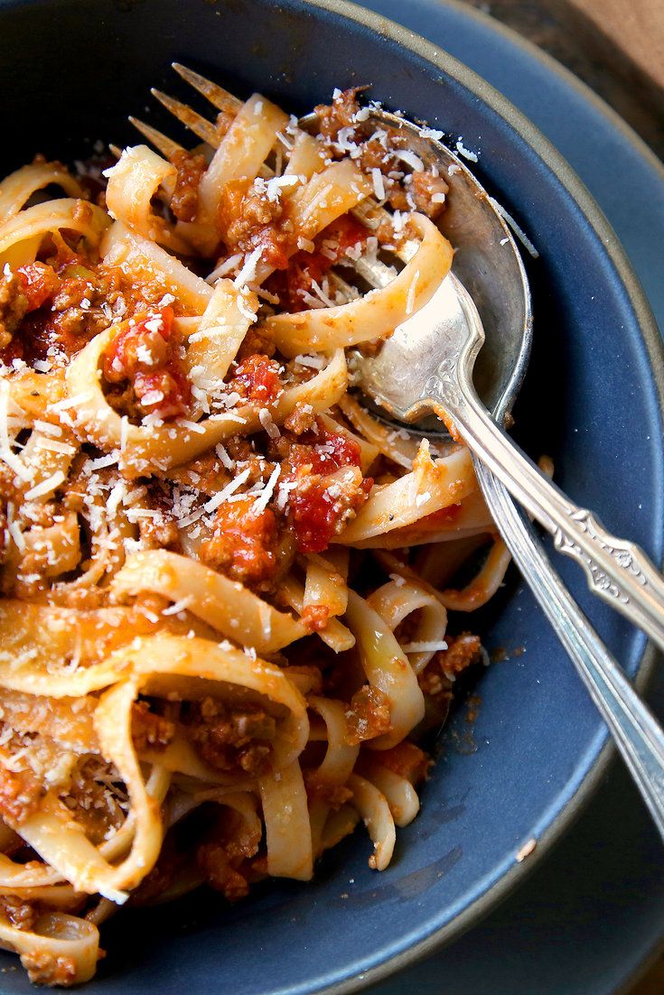 a bowl full of pasta with meat and cheese on top, ready to be eaten