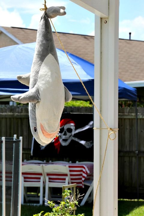 a stuffed shark hanging from the side of a white pole in front of a blue tent