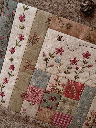 a close up of a patchwork quilt on the ground with flowers and hearts in it