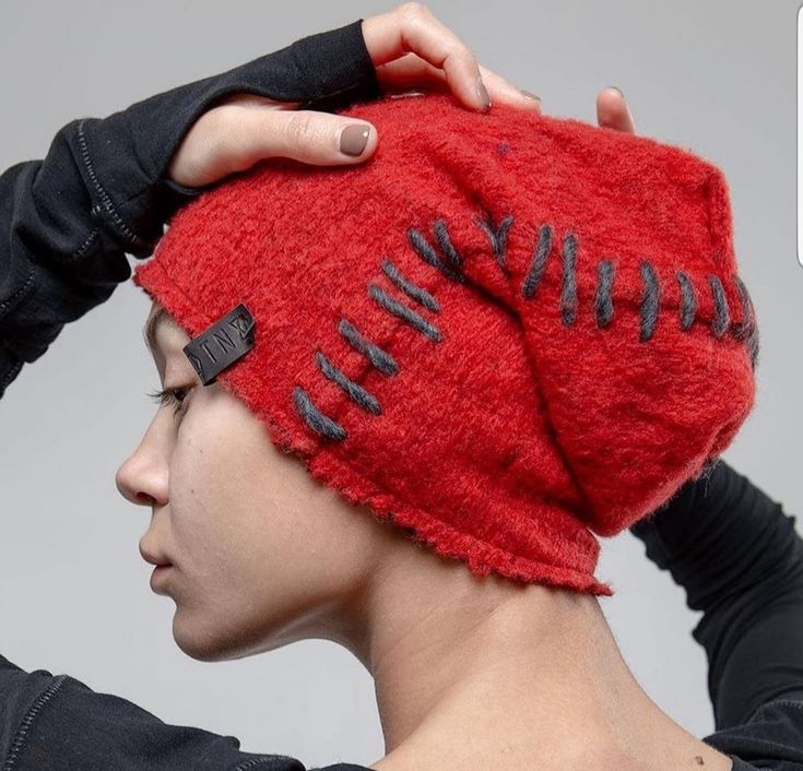 a woman wearing a red hat with black stitches on it