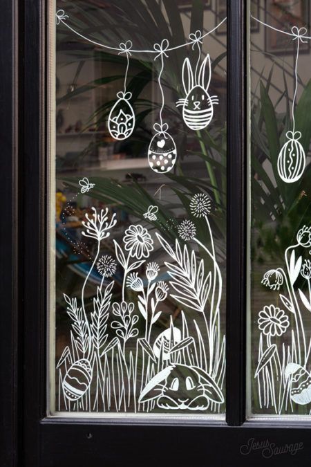 the window is decorated with easter eggs and flowers in white outline on black wood frame