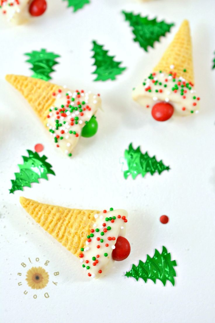 christmas cookies with icing and sprinkles are arranged on a white surface