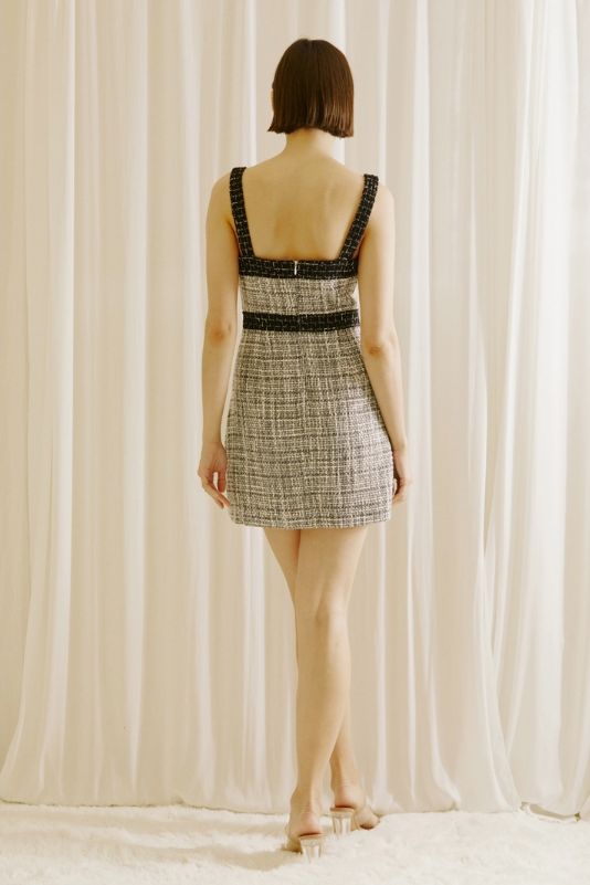 a woman standing in front of a white curtain with her back turned to the camera