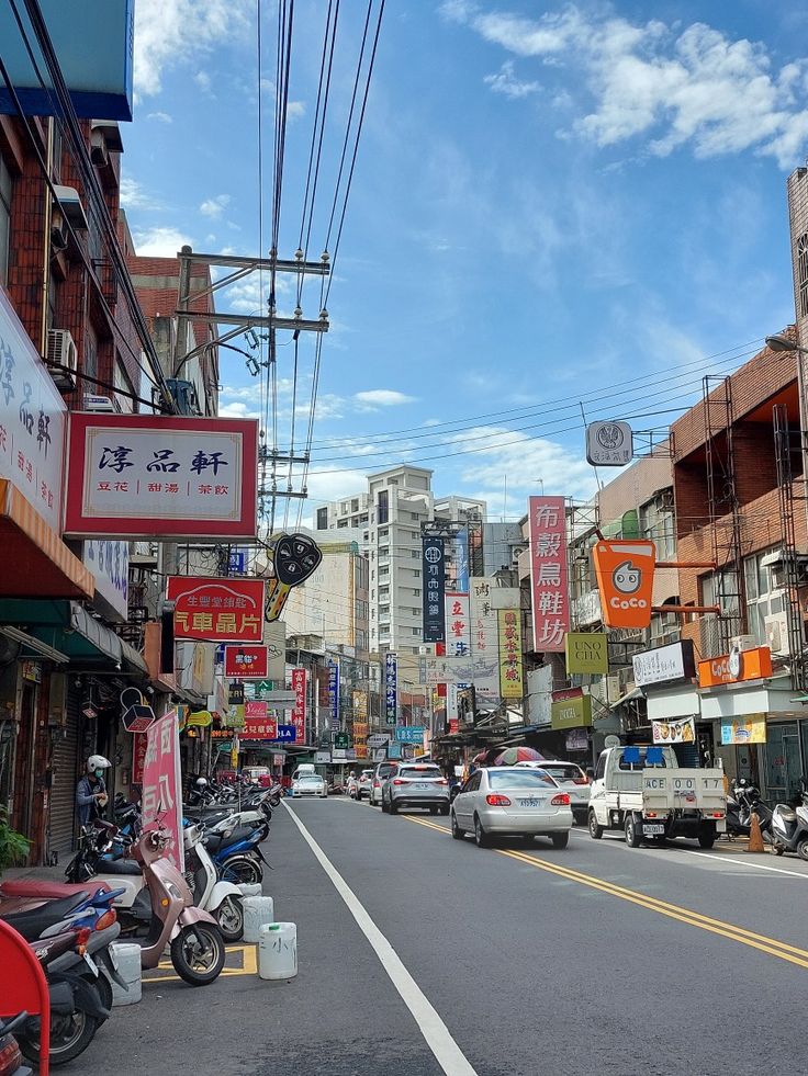 a city street filled with lots of traffic and tall buildings under blue skies in the background