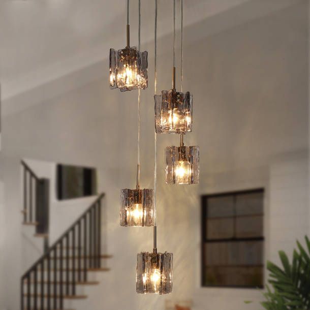 a chandelier hanging from the ceiling in a living room with stairs and windows