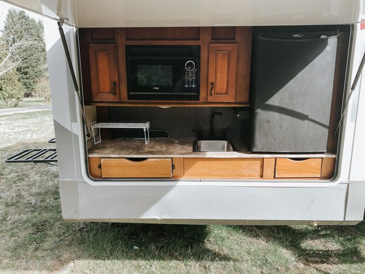 the kitchen area of an rv with wooden cabinets and appliances on it's side