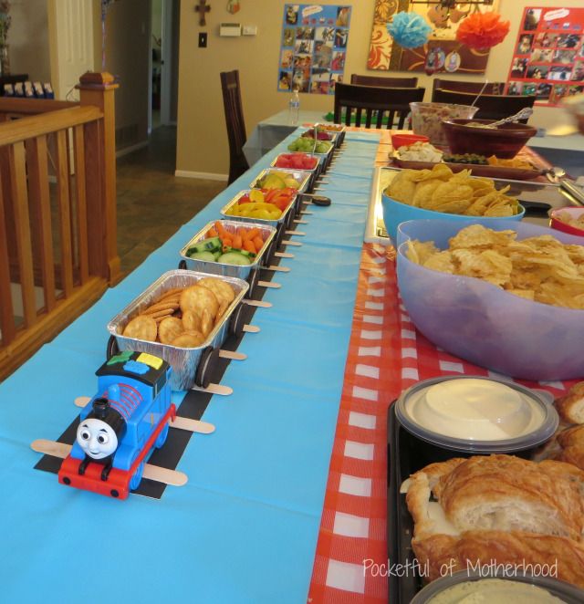 a table topped with trays of food and a thomas the tank engine train on it