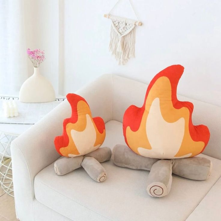 two pillows sitting on top of a white couch in front of a fireball shaped pillow