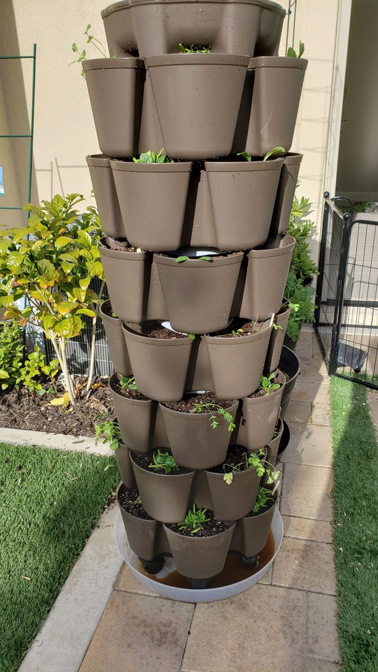 a large stack of potted plants in front of a house