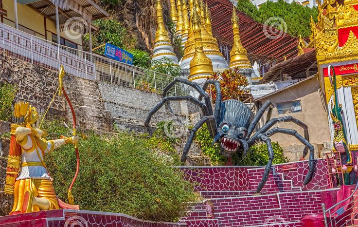 a giant spider statue sitting on top of a red and yellow wall next to a building