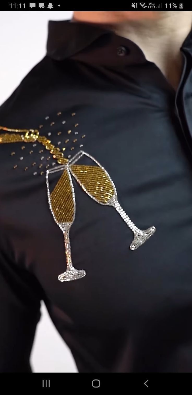 a woman wearing a black shirt with gold sequins on it and a glass of wine in her hand