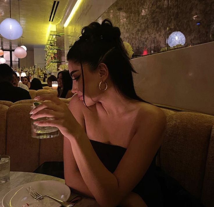 a woman sitting at a table with a glass in her hand