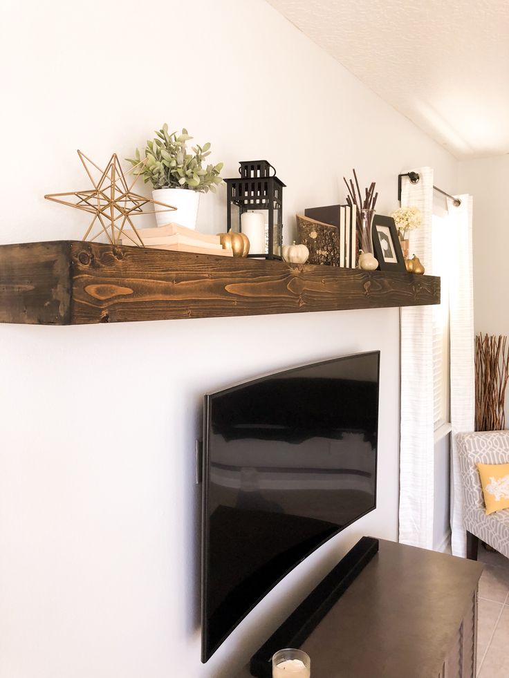 a flat screen tv sitting on top of a wooden shelf next to a fire place