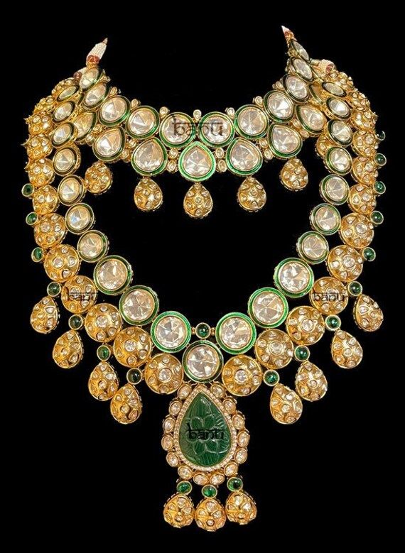 "Asmi - Gold Indian Jewelry Set w/ Green Meenakari, Emerald & Kundan for Brides Indian gold-plated jewelry w/ Kundan Gems and huge Emerald rock at the centre. Fit for any modern woman who appreciates the beauty of fine craftsmanship and design all in one stunning set! Clear Kundan stone all around adorns this bridal set. This jewelry is elaborated with embellished green meenakari detailed outlining the Kundan gems. This modern bridal jewelry is further accented with green precious emerald to add Luxury Gold Kundan Necklace With Meenakari, Luxury Kundan Necklace With Meenakari For Celebration, Luxury Gold Necklaces With Meenakari, Ornate Gold Kundan Necklace With 17 Jewels, Luxury Yellow Gold Kundan Necklace For Festive Occasions, Luxury Heavy Kundan Necklace For Formal Occasions, Luxury Meenakari Necklaces For Celebration, Luxury Gold Necklace With Stone Work, Luxury Necklaces With Stone Work For Festivals