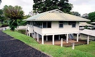 a white house sitting on the side of a road next to a lush green field