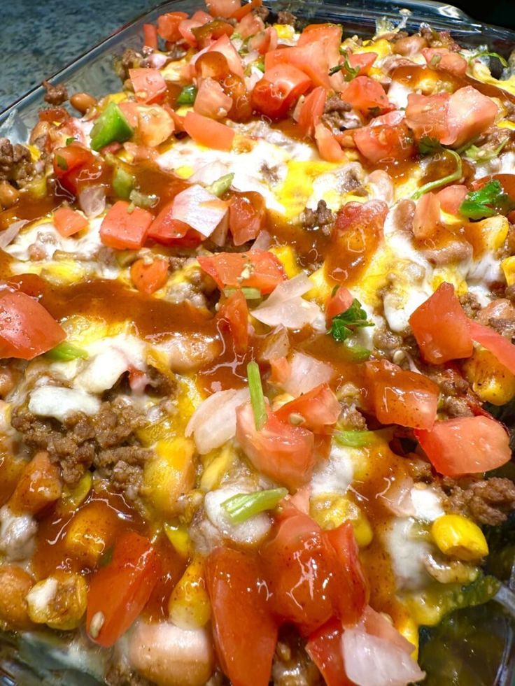 a casserole dish with tomatoes, corn and cheese on it is ready to be eaten