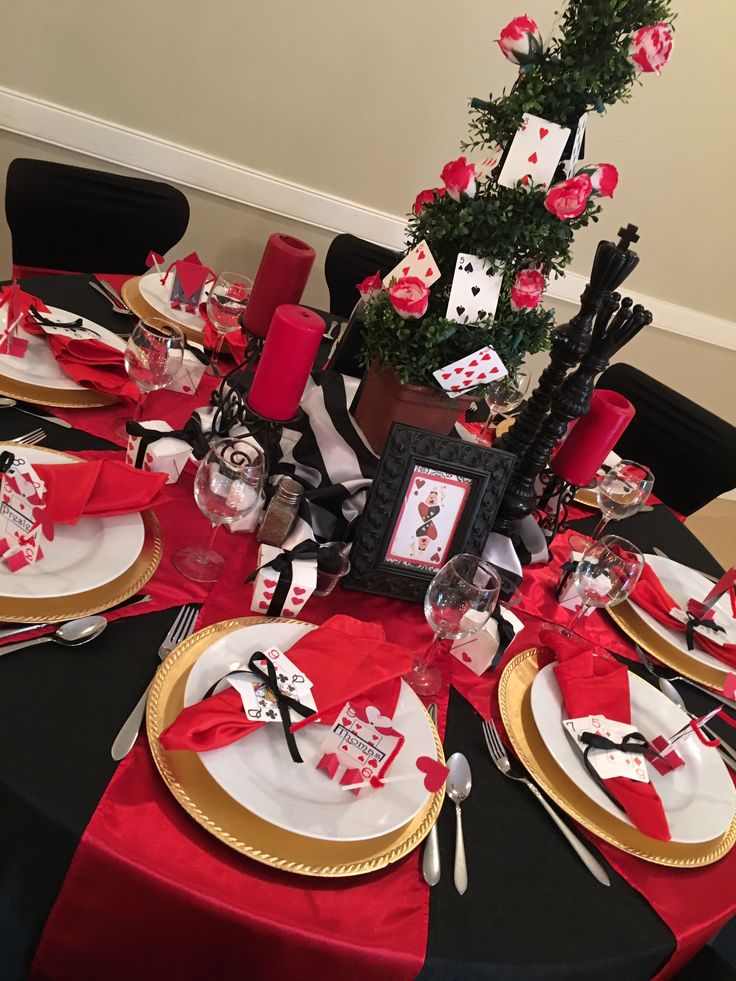 the table is set with red and black place settings, silverware, and cards