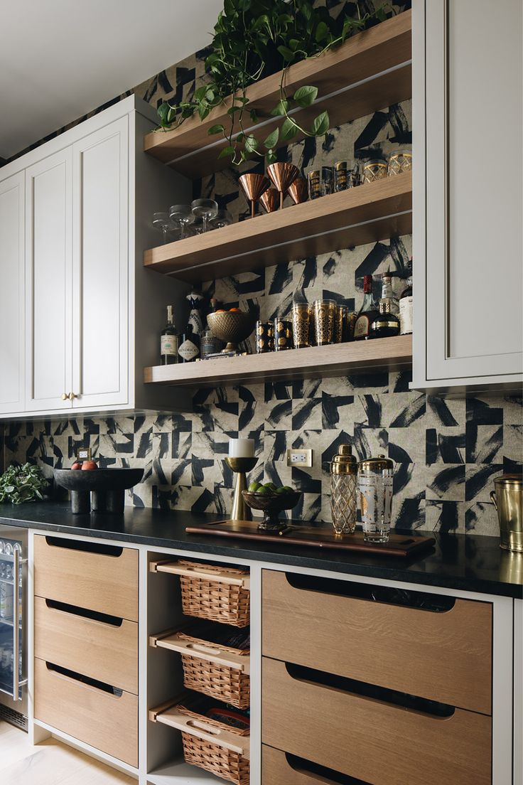 a kitchen with white cabinets and black counter tops next to shelves filled with pots and pans