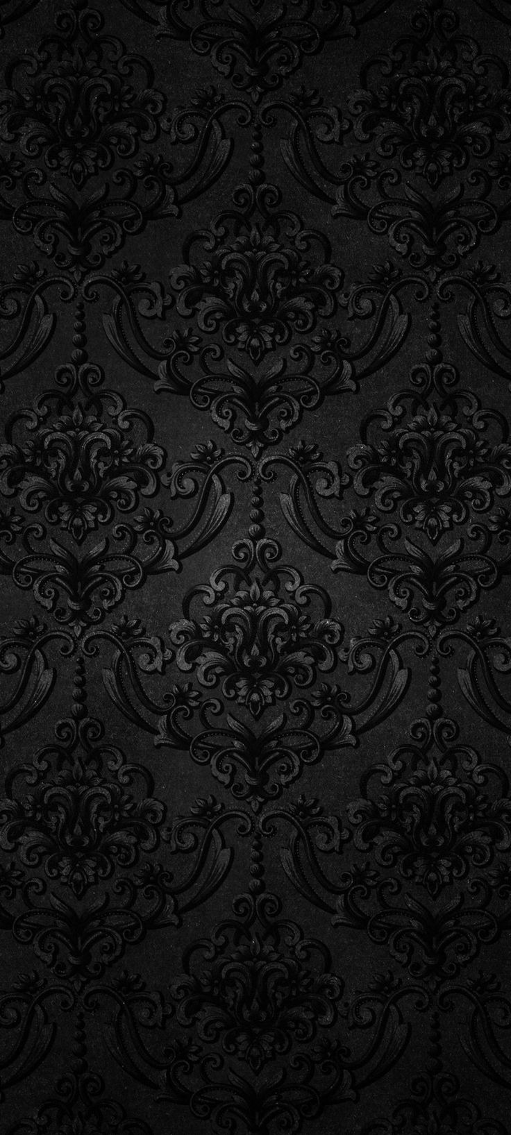 a black wallpaper with ornate designs and swirls in the center, on a dark background