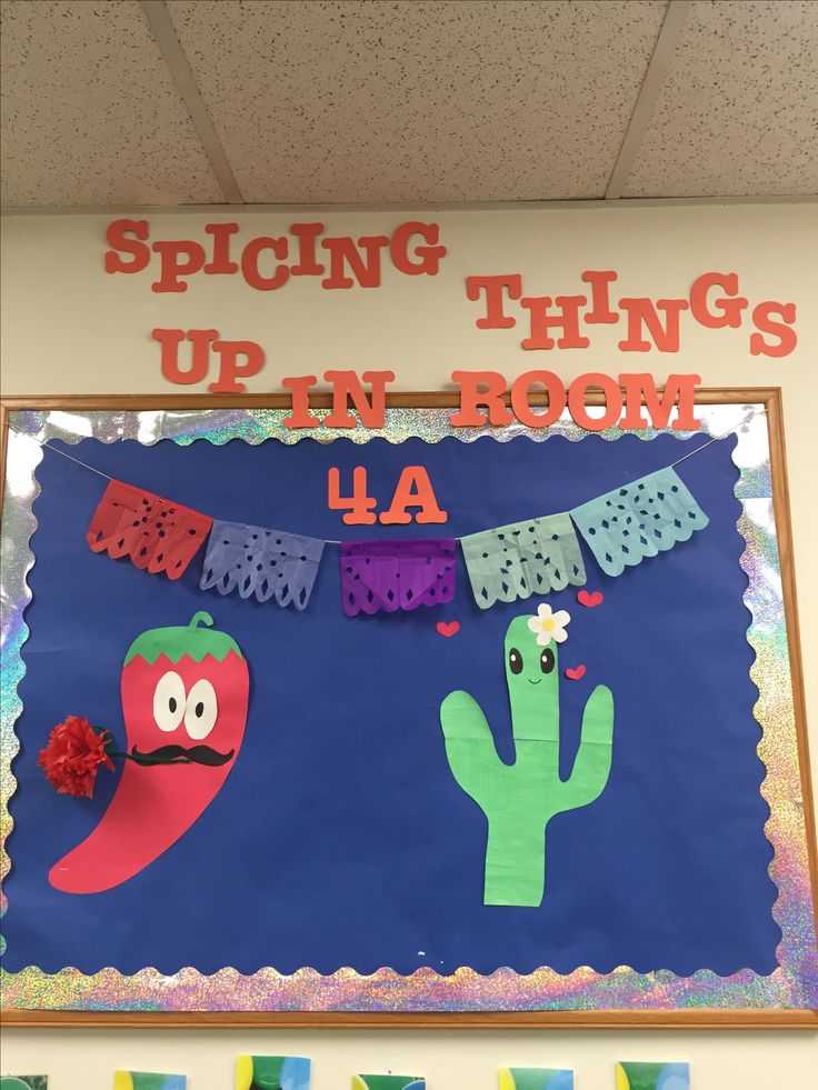 a bulletin board decorated with paper cutouts and cactuses on the front, hanging from a string