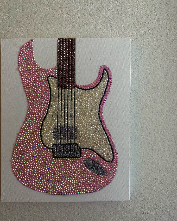 a painting of a guitar with pink and white dots on it's body is hanging on the wall