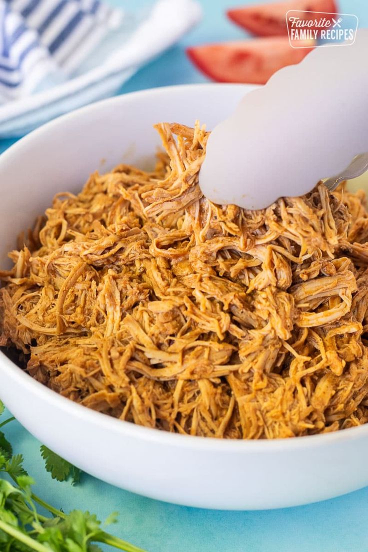 shredded meat being spooned into a white bowl