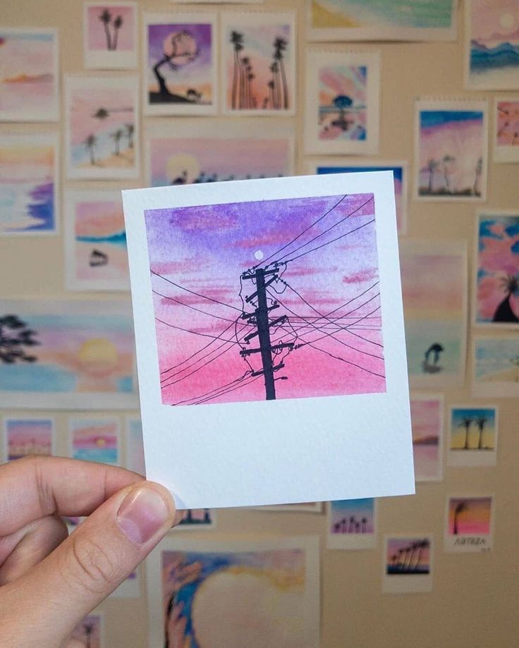 a person holding up a piece of paper with an image of a telephone pole in the background