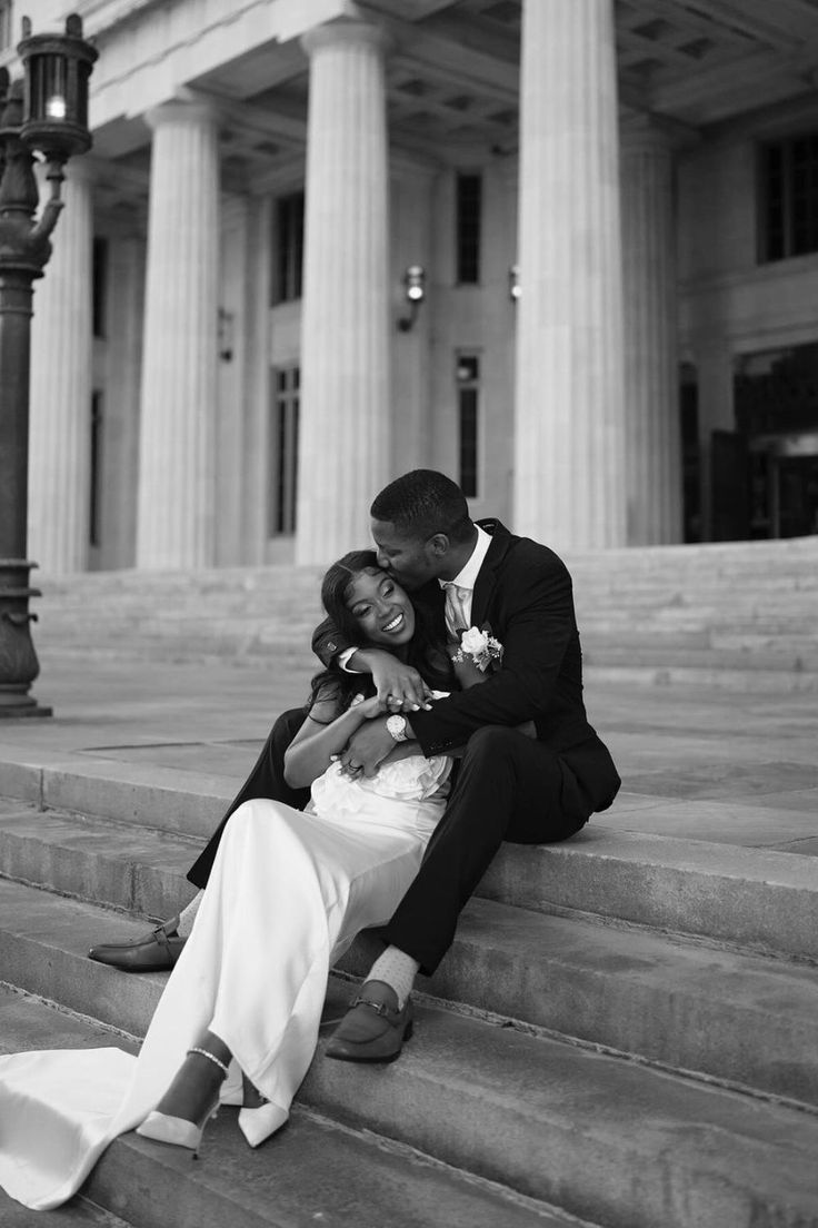 a bride and groom sitting on steps in front of a building