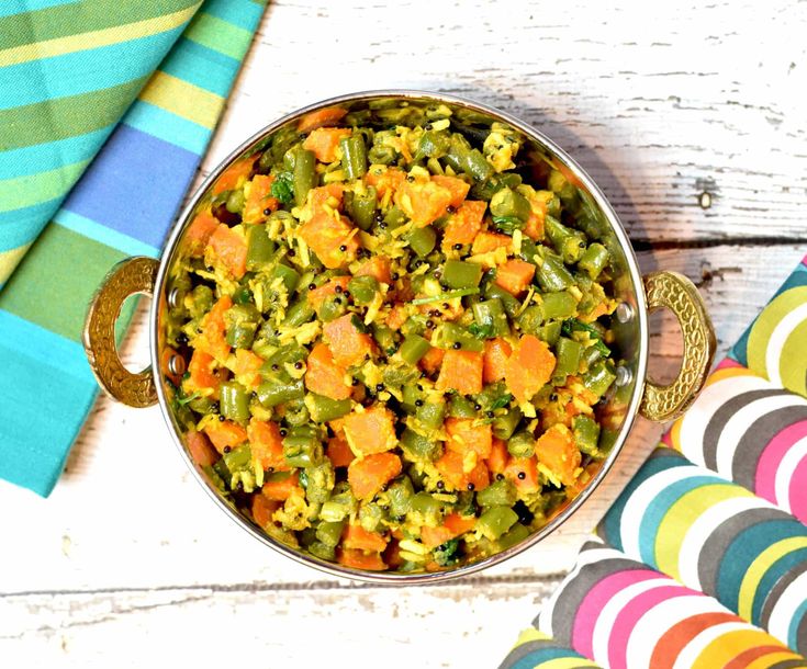 a bowl filled with green beans and carrots on top of a colorful table cloth