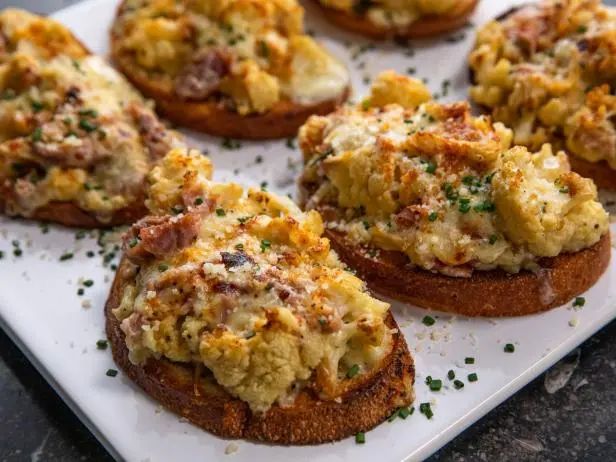 several open faced sandwiches are on a white plate with sprinkled parmesan