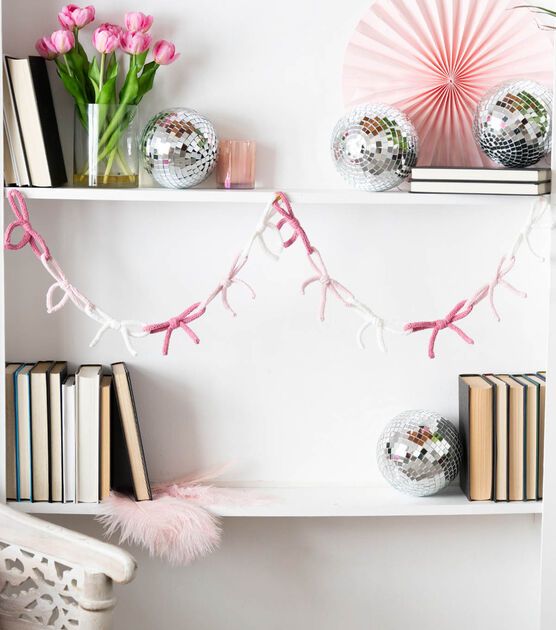 a white shelf topped with books and pink decorations