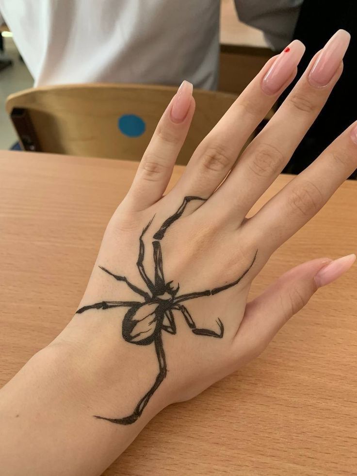 a woman's hand with a black spider tattoo on the middle of her palm