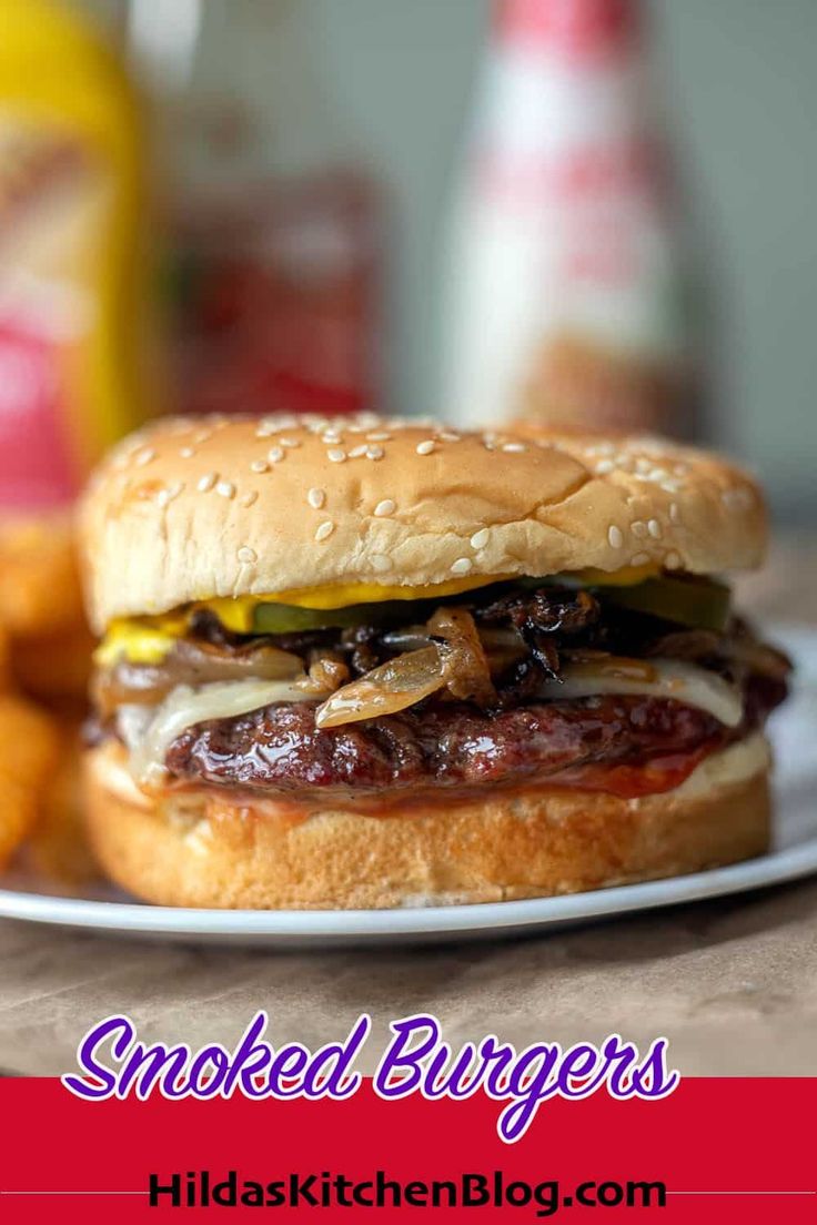 a hamburger on a plate next to some tater tots