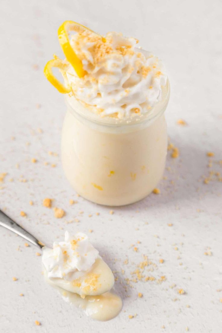 a dessert with whipped cream and lemon wedges on the rim next to a spoon