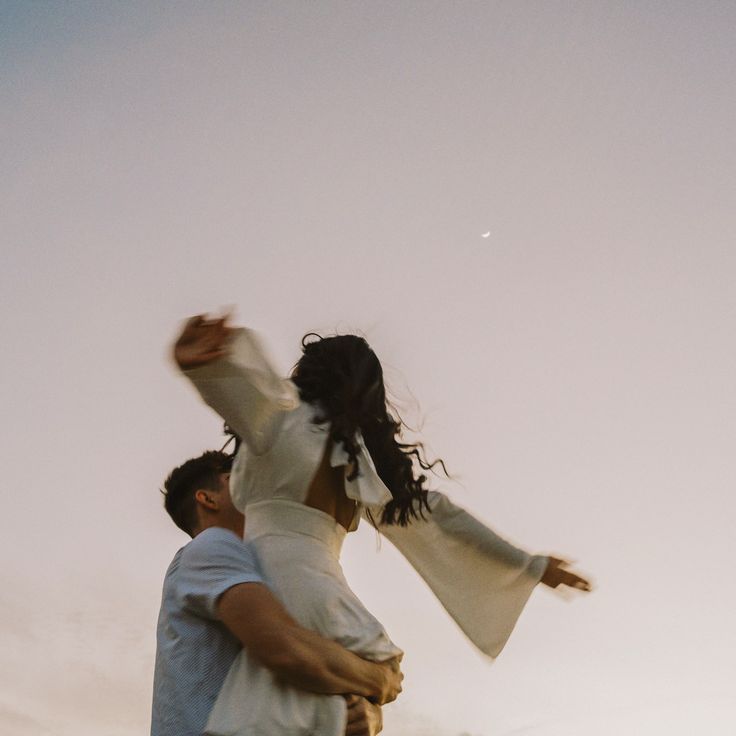 a man carrying a woman in his arms as they fly through the air at sunset