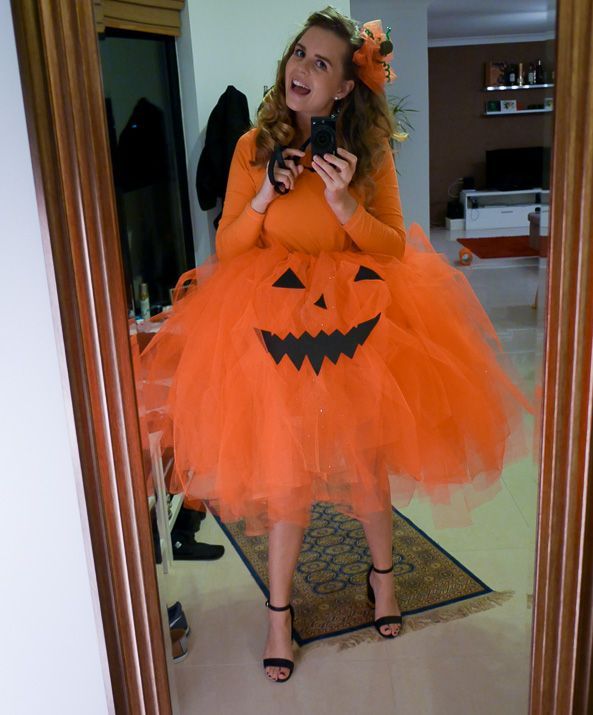 a woman in an orange halloween costume taking a selfie