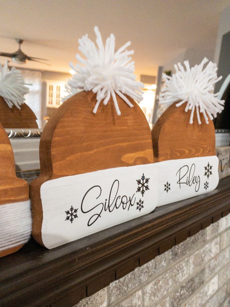 three wooden hats sitting on top of a fireplace mantel covered in snowflakes