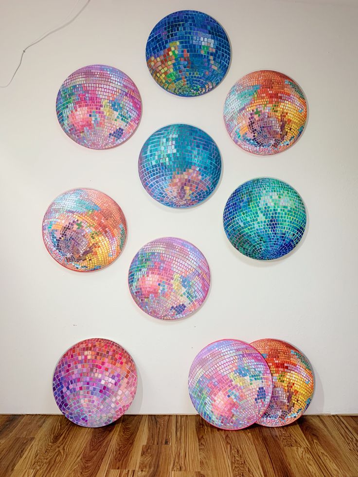 a group of colorful plates sitting on top of a wooden floor next to a white wall