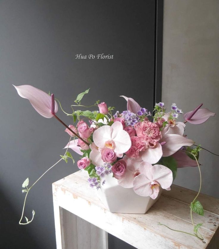 a white vase filled with pink and purple flowers