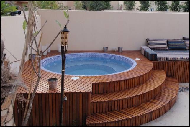 an above ground pool with steps leading up to it and a hot tub in the middle