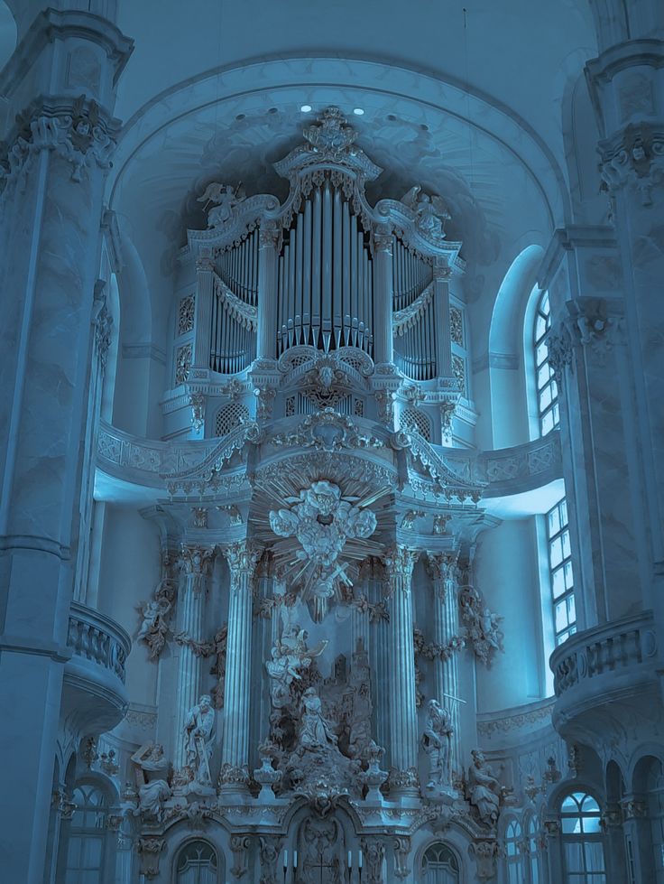 an ornate pipe organ in a church with blue light coming from the windows and ceiling