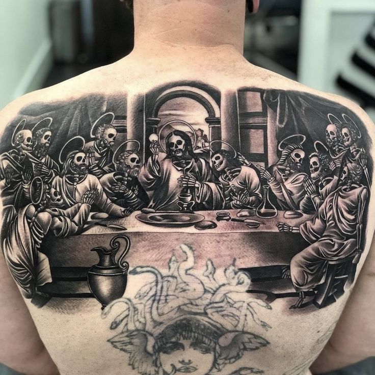 a man's back with a black and grey tattoo on his upper half that depicts the last supper of jesus