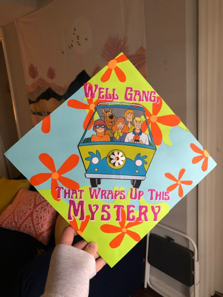 a person holding up a yellow and blue graduation cap with the words web gang that wraps up this mystery on it