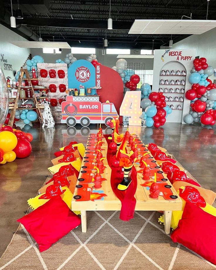 a table set up with red, yellow and blue decorations for a fireman's birthday party