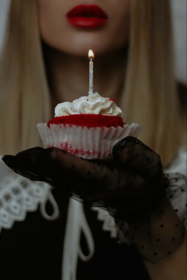 a woman holding a cupcake with a candle in it